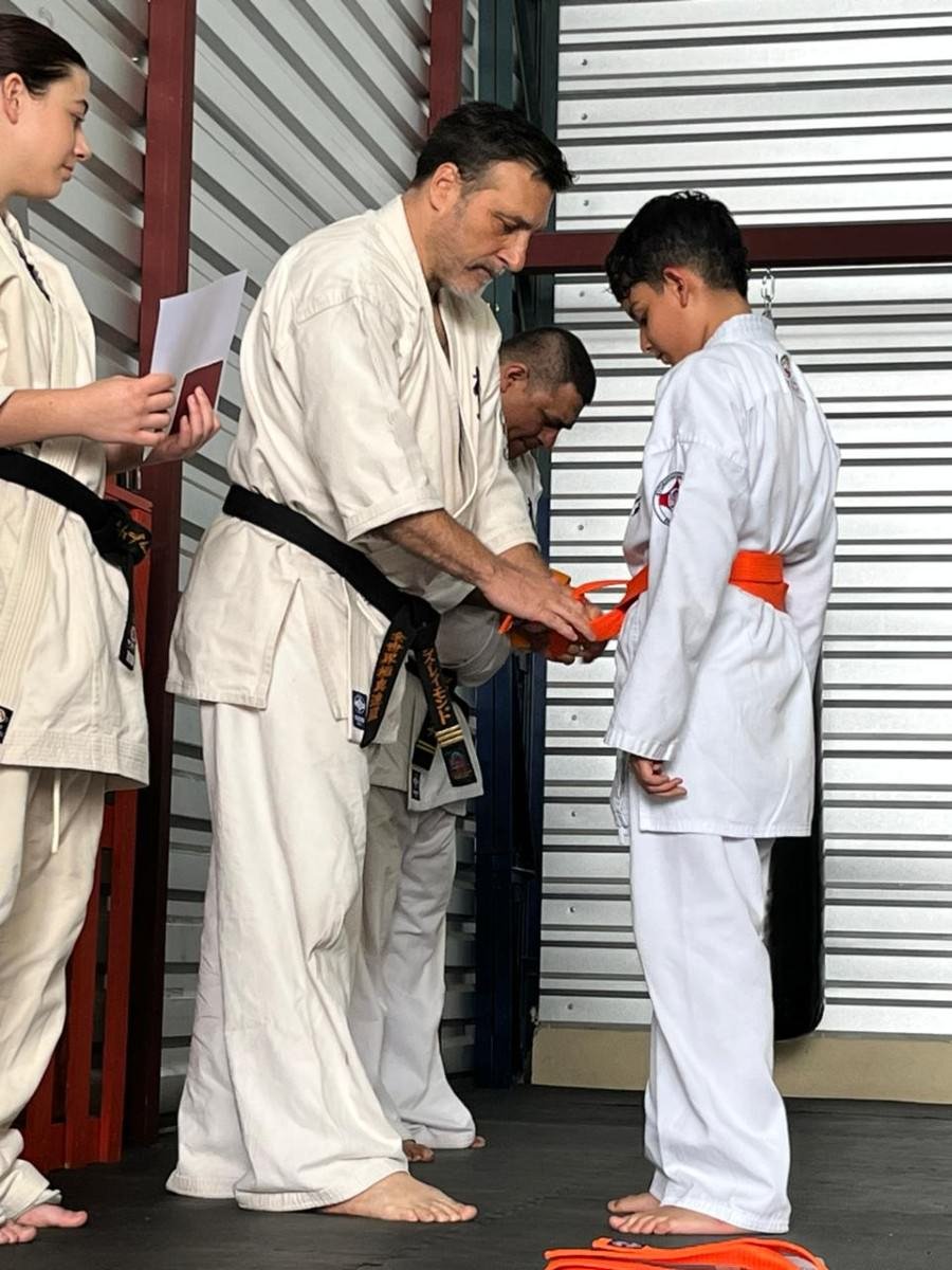 Instructor guiando ejercicios de karate Kyokushin a alumnos infantiles en Heredia